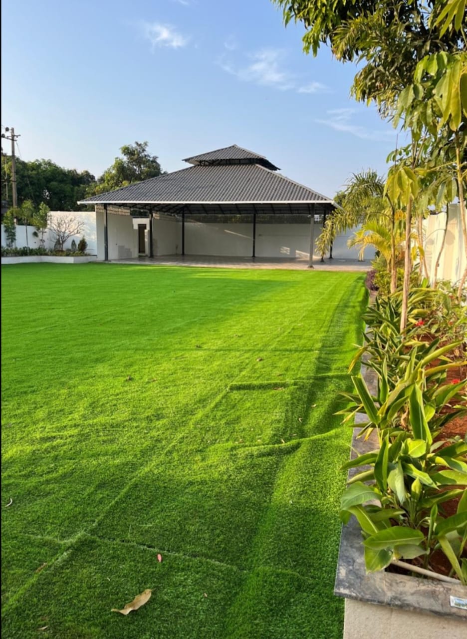 Open green lawn and covered pavilion at The Heaven Garden Lawns during daytime